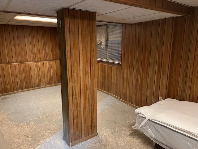 basement with a paneled ceiling and wooden walls