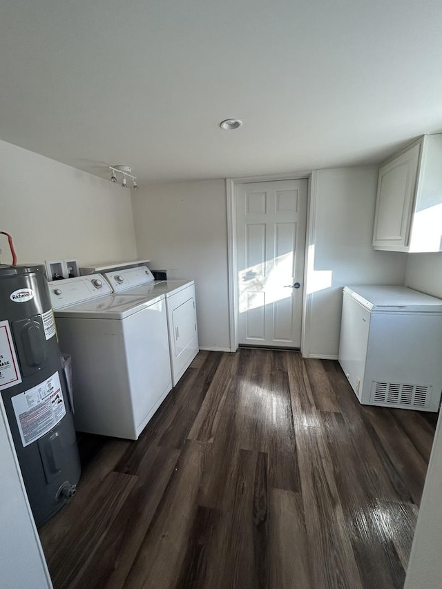 clothes washing area featuring cabinets, dark hardwood / wood-style flooring, washer and clothes dryer, and electric water heater