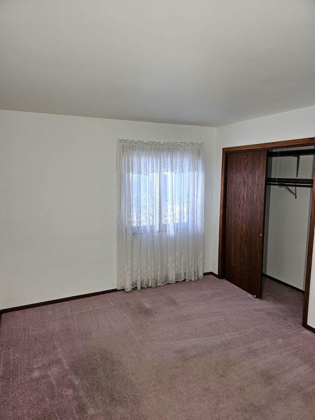 unfurnished bedroom featuring light carpet and a closet