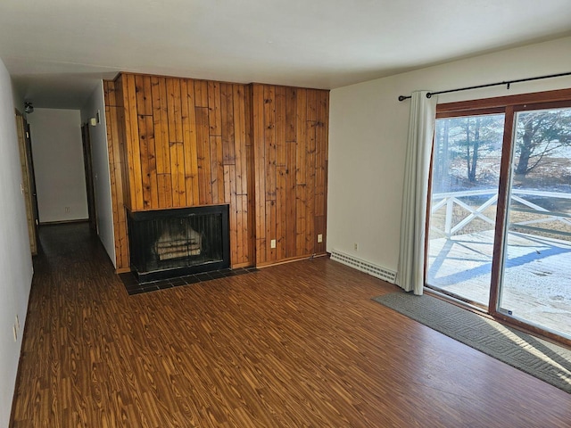 unfurnished living room with dark wood-type flooring, a baseboard radiator, and wood walls