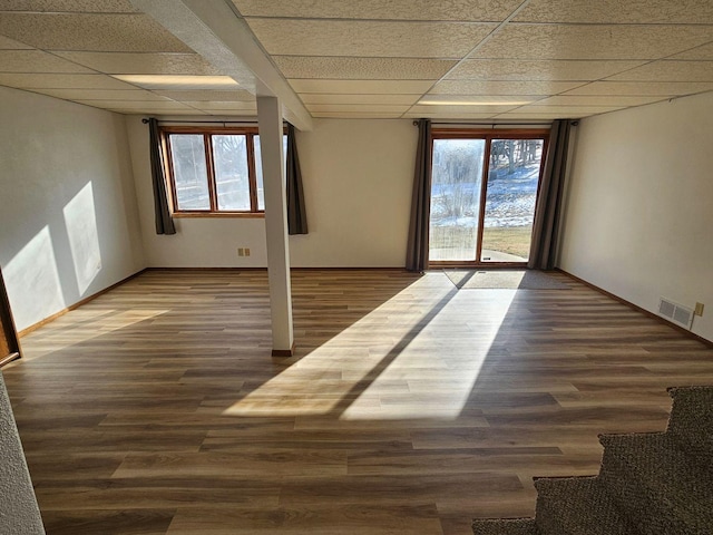 spare room featuring dark wood-type flooring and a drop ceiling