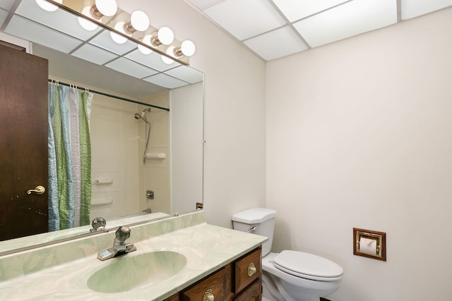 full bathroom with shower / tub combo with curtain, vanity, toilet, and a drop ceiling