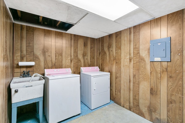 laundry area with washer and clothes dryer, electric panel, and wooden walls