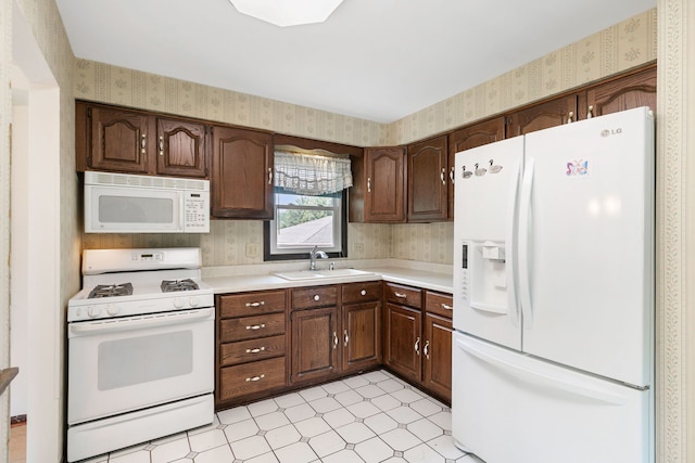 kitchen with dark brown cabinetry, sink, and white appliances