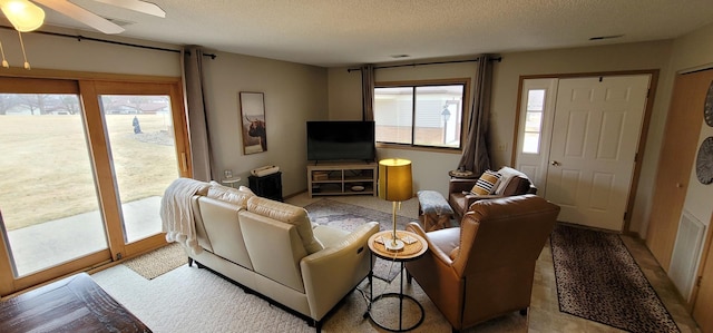 living room with ceiling fan and a textured ceiling