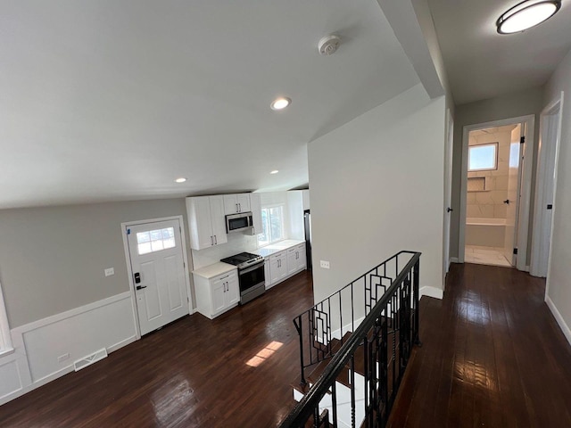 hallway with an upstairs landing, a wainscoted wall, recessed lighting, and dark wood-type flooring