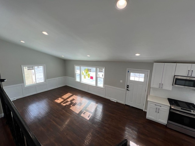 kitchen with a wainscoted wall, dark wood-style flooring, stainless steel appliances, light countertops, and white cabinetry