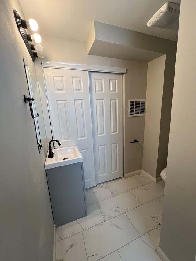 bathroom featuring visible vents, baseboards, toilet, marble finish floor, and vanity