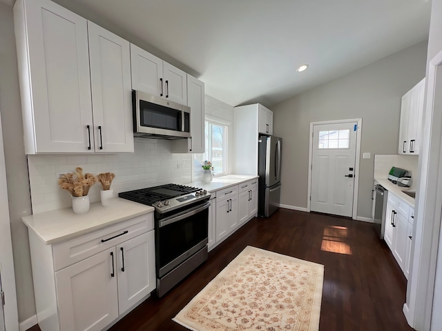 kitchen featuring stainless steel appliances, lofted ceiling, backsplash, and light countertops