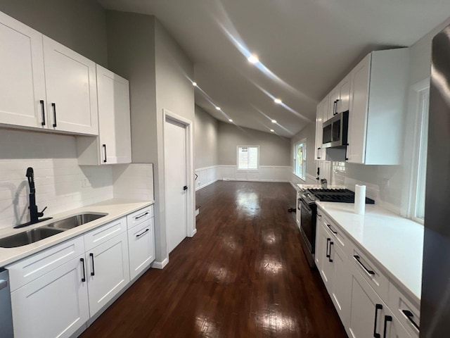 kitchen featuring a sink, dark wood-type flooring, light countertops, vaulted ceiling, and appliances with stainless steel finishes