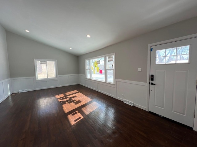 entryway with visible vents, lofted ceiling, dark wood-style floors, and a wainscoted wall