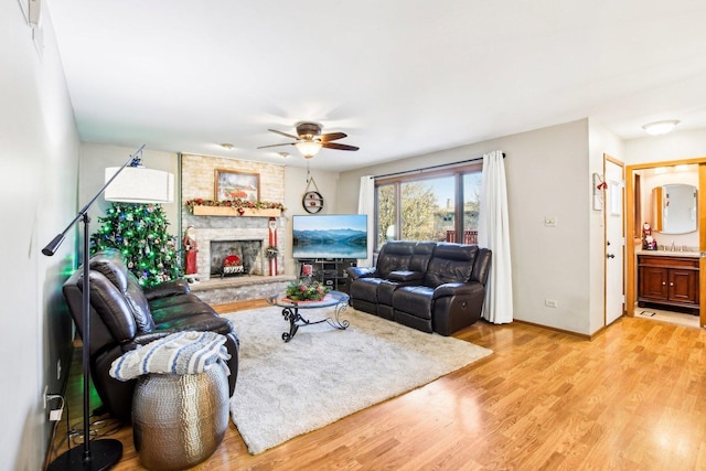 living room with sink, light hardwood / wood-style flooring, a large fireplace, and ceiling fan