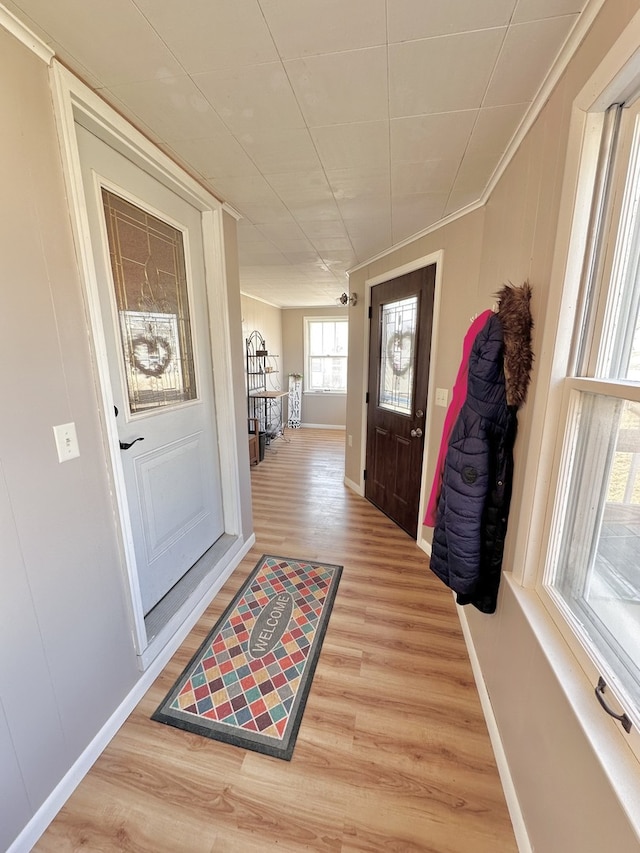 doorway to outside with hardwood / wood-style flooring and crown molding