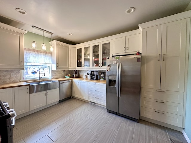 kitchen featuring stainless steel appliances, white cabinetry, sink, and pendant lighting