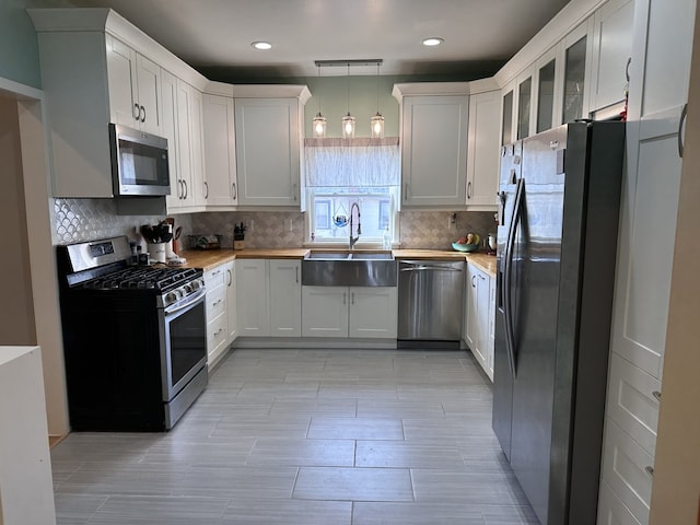 kitchen featuring appliances with stainless steel finishes, sink, hanging light fixtures, and white cabinets