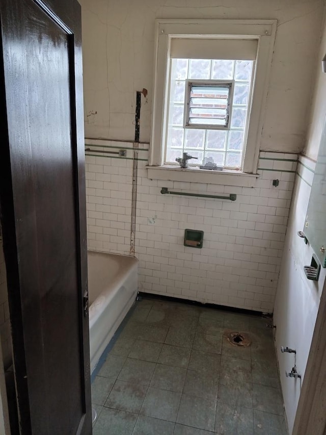 bathroom with a bathtub, tile patterned flooring, and tile walls