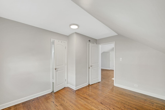 additional living space with vaulted ceiling and light hardwood / wood-style flooring