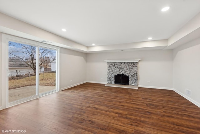 unfurnished living room with a stone fireplace and dark hardwood / wood-style flooring