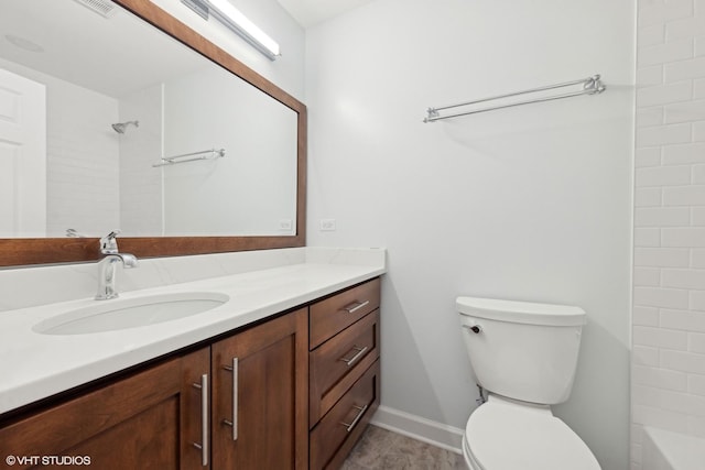 bathroom featuring vanity, tiled shower, and toilet