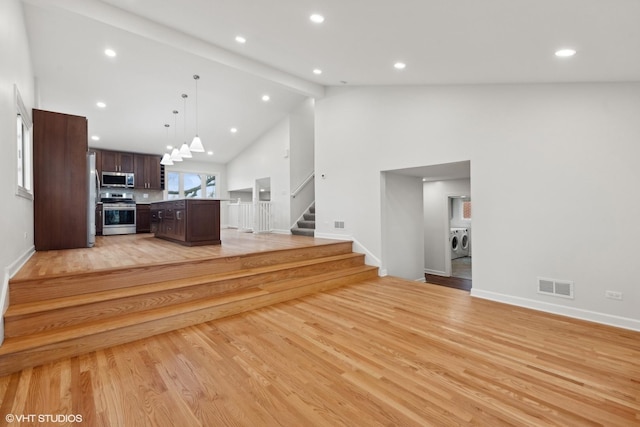 unfurnished living room with beam ceiling, high vaulted ceiling, washing machine and clothes dryer, and light hardwood / wood-style floors