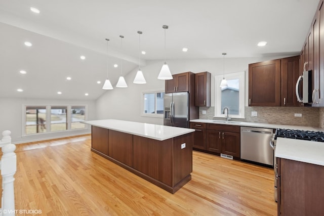 kitchen with sink, light hardwood / wood-style flooring, hanging light fixtures, stainless steel appliances, and a center island