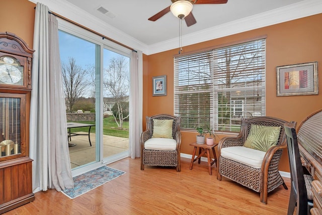 living area featuring light hardwood / wood-style flooring, ornamental molding, and ceiling fan