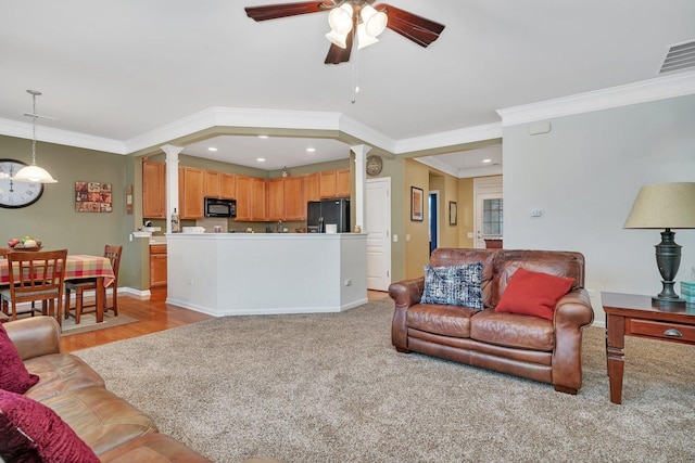 living room featuring crown molding, light colored carpet, ceiling fan, and ornate columns