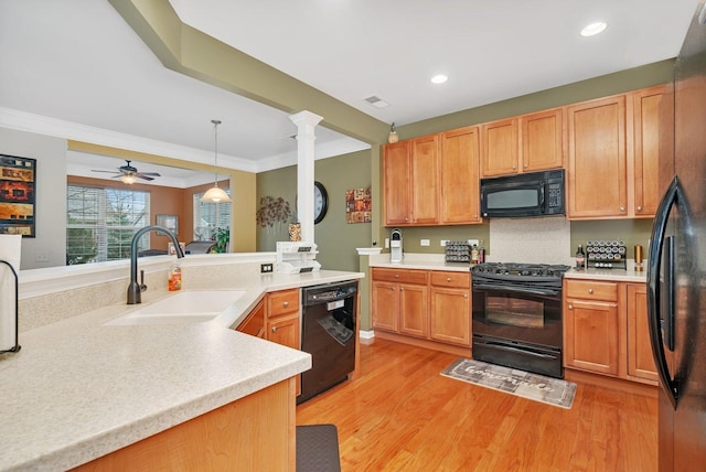 kitchen featuring sink, hanging light fixtures, light hardwood / wood-style floors, ornamental molding, and black appliances