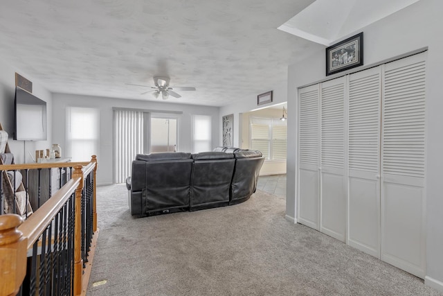 carpeted living room with a textured ceiling and ceiling fan