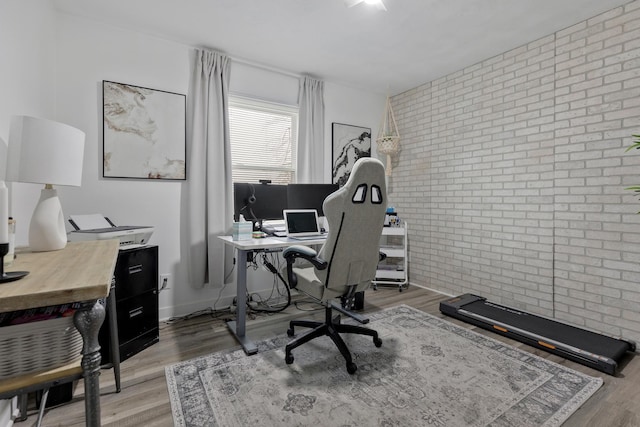 home office with hardwood / wood-style floors and brick wall