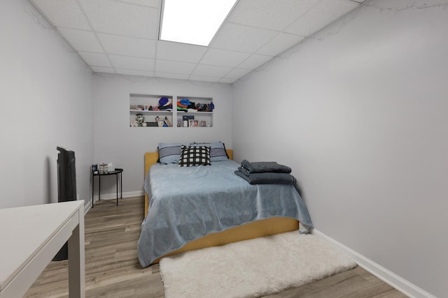 bedroom with a drop ceiling and light hardwood / wood-style floors