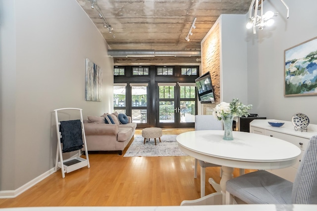 interior space featuring track lighting, french doors, a towering ceiling, and light wood finished floors