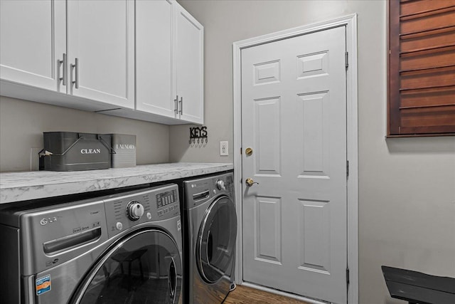 clothes washing area featuring washing machine and dryer and cabinets