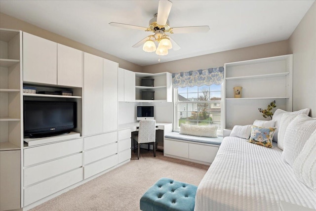 bedroom with ceiling fan, built in desk, and light carpet