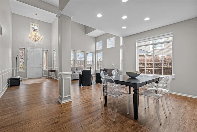 dining room with ornate columns, dark hardwood / wood-style floors, a chandelier, and a high ceiling