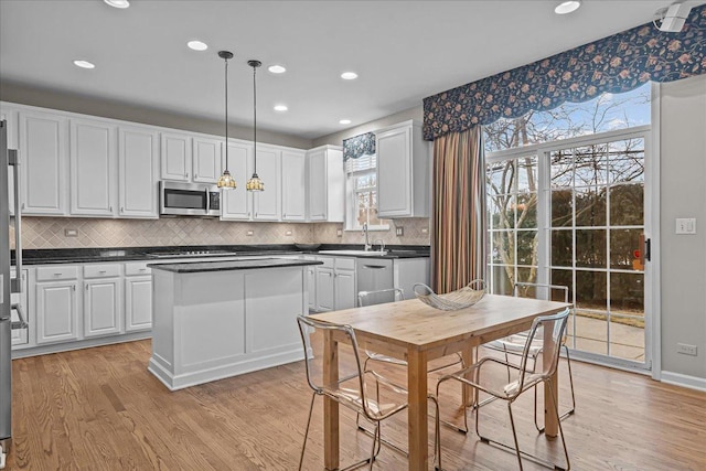 kitchen featuring white cabinetry, hanging light fixtures, a wealth of natural light, and light wood-type flooring