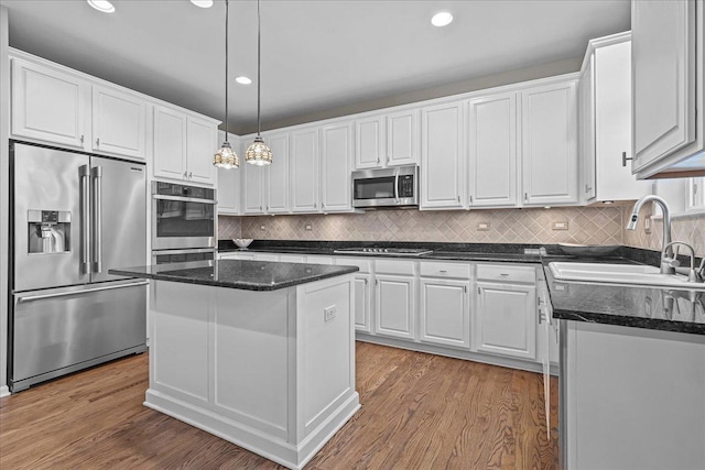 kitchen with pendant lighting, sink, appliances with stainless steel finishes, white cabinetry, and a kitchen island