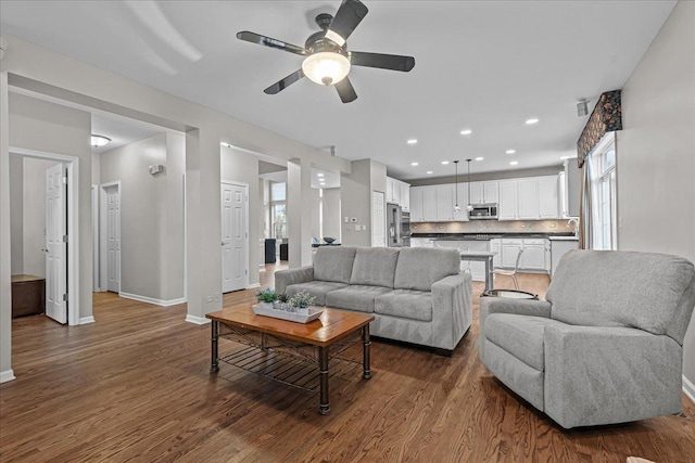 living room featuring ceiling fan, plenty of natural light, and dark hardwood / wood-style flooring