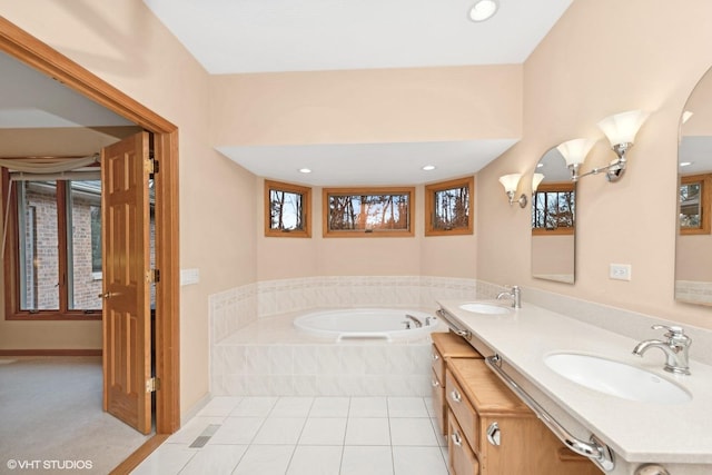 bathroom with plenty of natural light, vanity, tile patterned flooring, and tiled tub