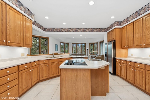 kitchen featuring stainless steel refrigerator with ice dispenser, a kitchen island with sink, sink, and black electric stovetop