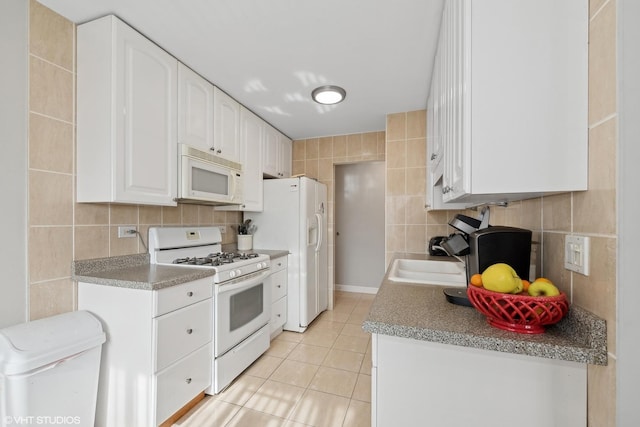 kitchen featuring white cabinetry, tile walls, backsplash, and white appliances