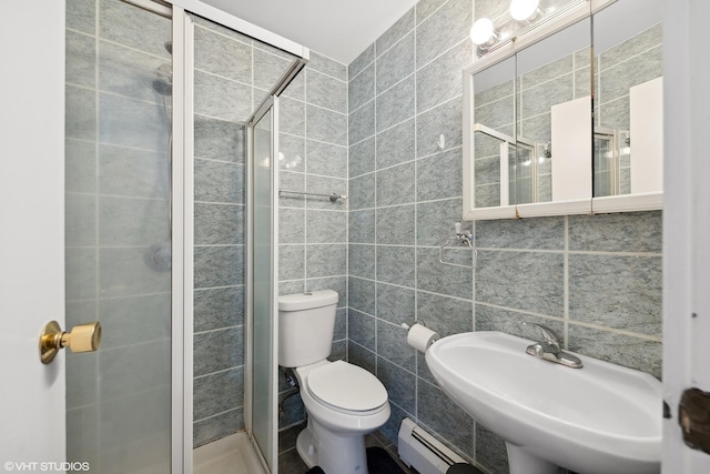 bathroom with a baseboard radiator, sink, tile walls, an enclosed shower, and toilet