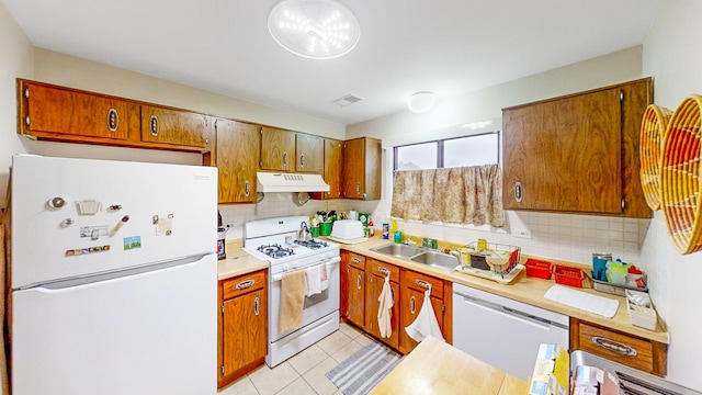 kitchen with white appliances, light tile patterned floors, sink, and backsplash