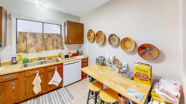 kitchen with tasteful backsplash, sink, light tile patterned floors, and dishwashing machine