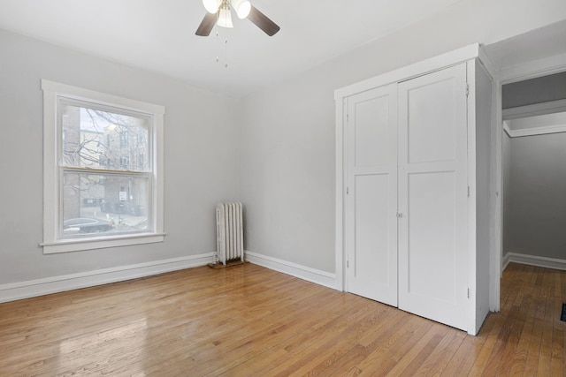 unfurnished bedroom featuring radiator, light hardwood / wood-style flooring, a closet, and ceiling fan