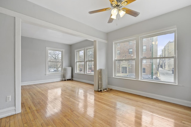 empty room with radiator, light hardwood / wood-style floors, and ceiling fan