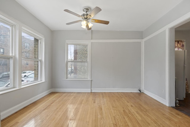 spare room with ceiling fan, a wealth of natural light, and light hardwood / wood-style floors