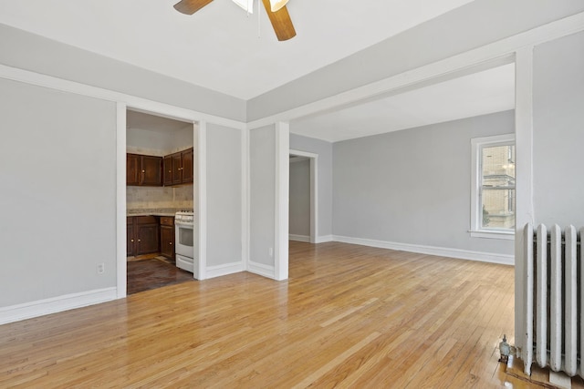 unfurnished living room with radiator, ceiling fan, and light hardwood / wood-style flooring