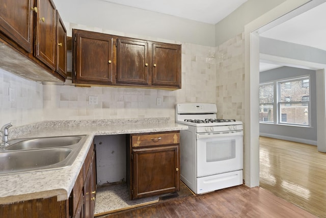 kitchen featuring sink, dark hardwood / wood-style flooring, decorative backsplash, white range with gas stovetop, and dark brown cabinets