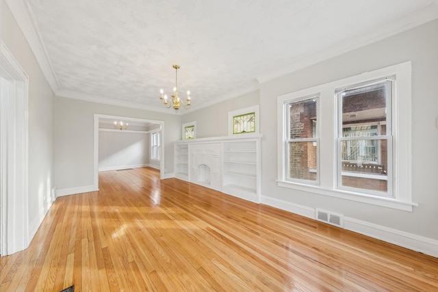 interior space with ornamental molding, a fireplace, a chandelier, and light hardwood / wood-style flooring